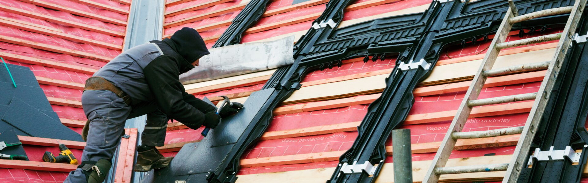A roofer replacing the tiles on a house roof.