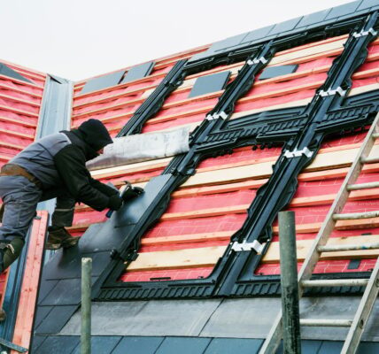 A roofer replacing the tiles on a house roof.