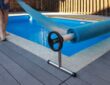 Man covers swimming pool with cover for protection against dirt, leaves, heating and cooling water.
