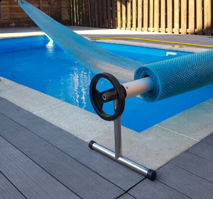 Man covers swimming pool with cover for protection against dirt, leaves, heating and cooling water.